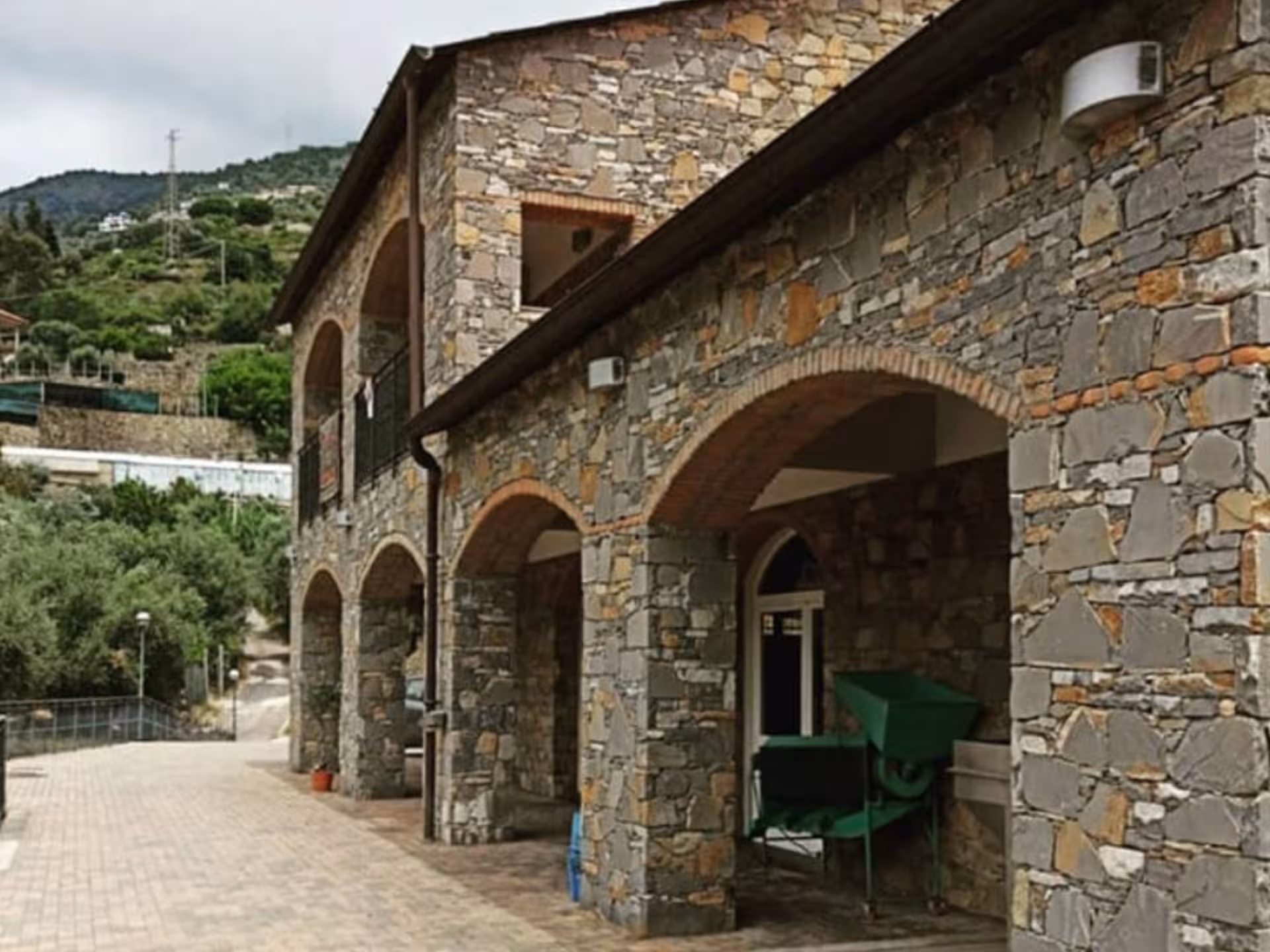 Stone building surrounded by olive trees at the Taggia olive mill, perfect for guided tasting tours.
