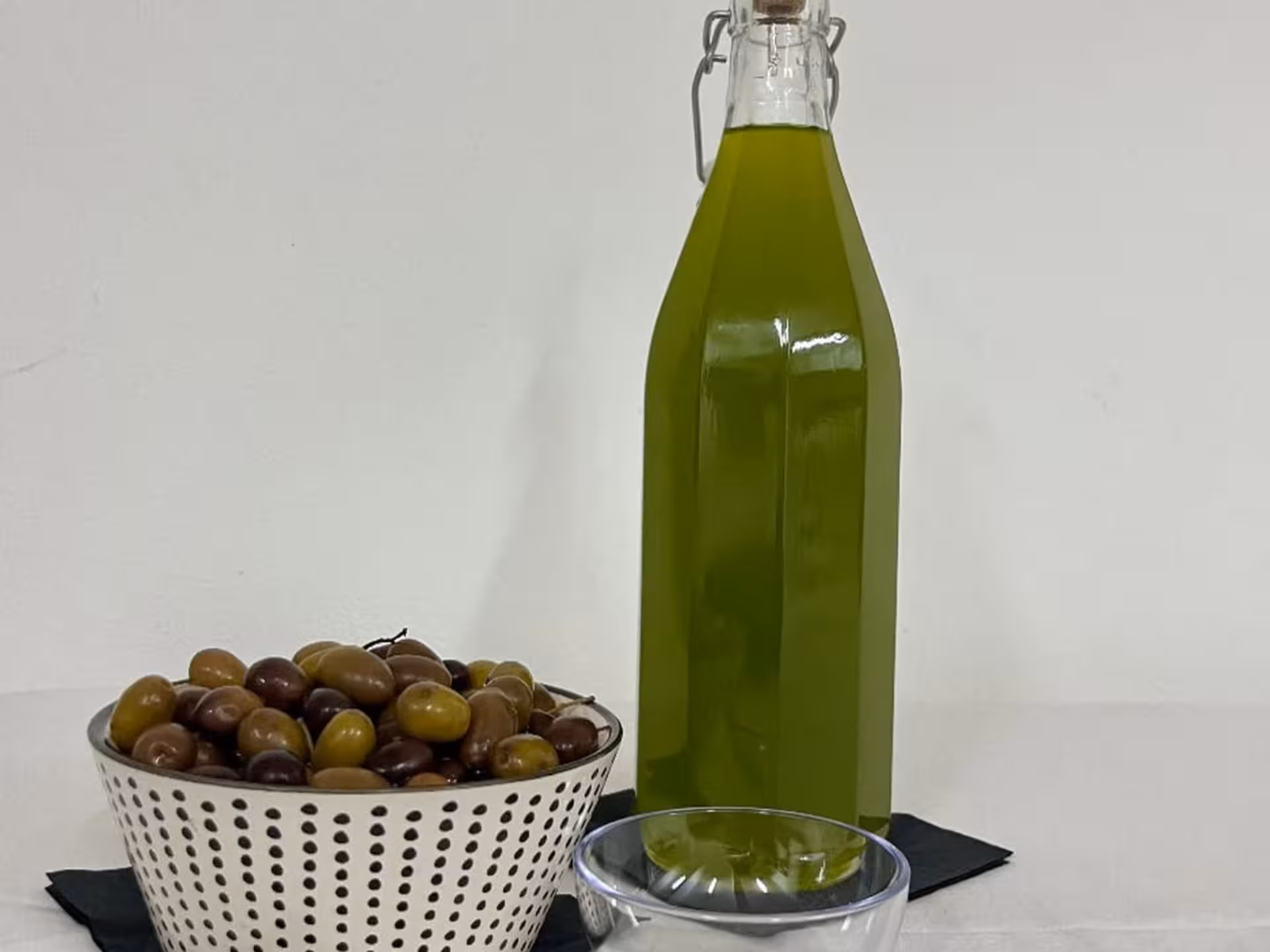 Basket of Taggiasca olives and a bottle of olive oil for tasting at Taggia's renowned olive mill tour.
