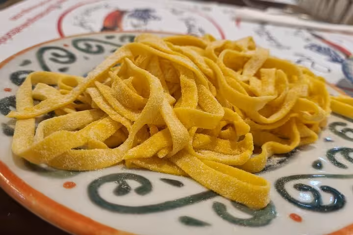 Freshly made tagliatelle on a decorative plate, part of a private cooking class in Rome featuring authentic Italian pasta.