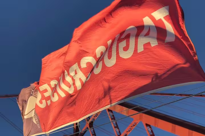 Vibrant red Tagus Cruises flag flutters against the blue sky on a morning sailing tour from Lisbon.