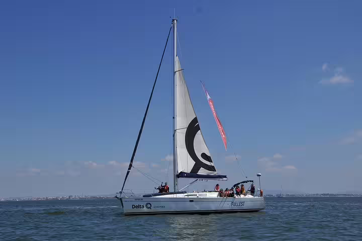 Sailboat on Tagus River under clear skies during Lisbon morning tour, showcasing serene sailing experience.