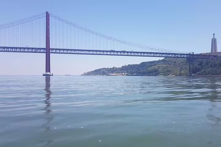 Scenic view of the 25 de Abril Bridge and Christ the King statue from the Tagus River in Lisbon.