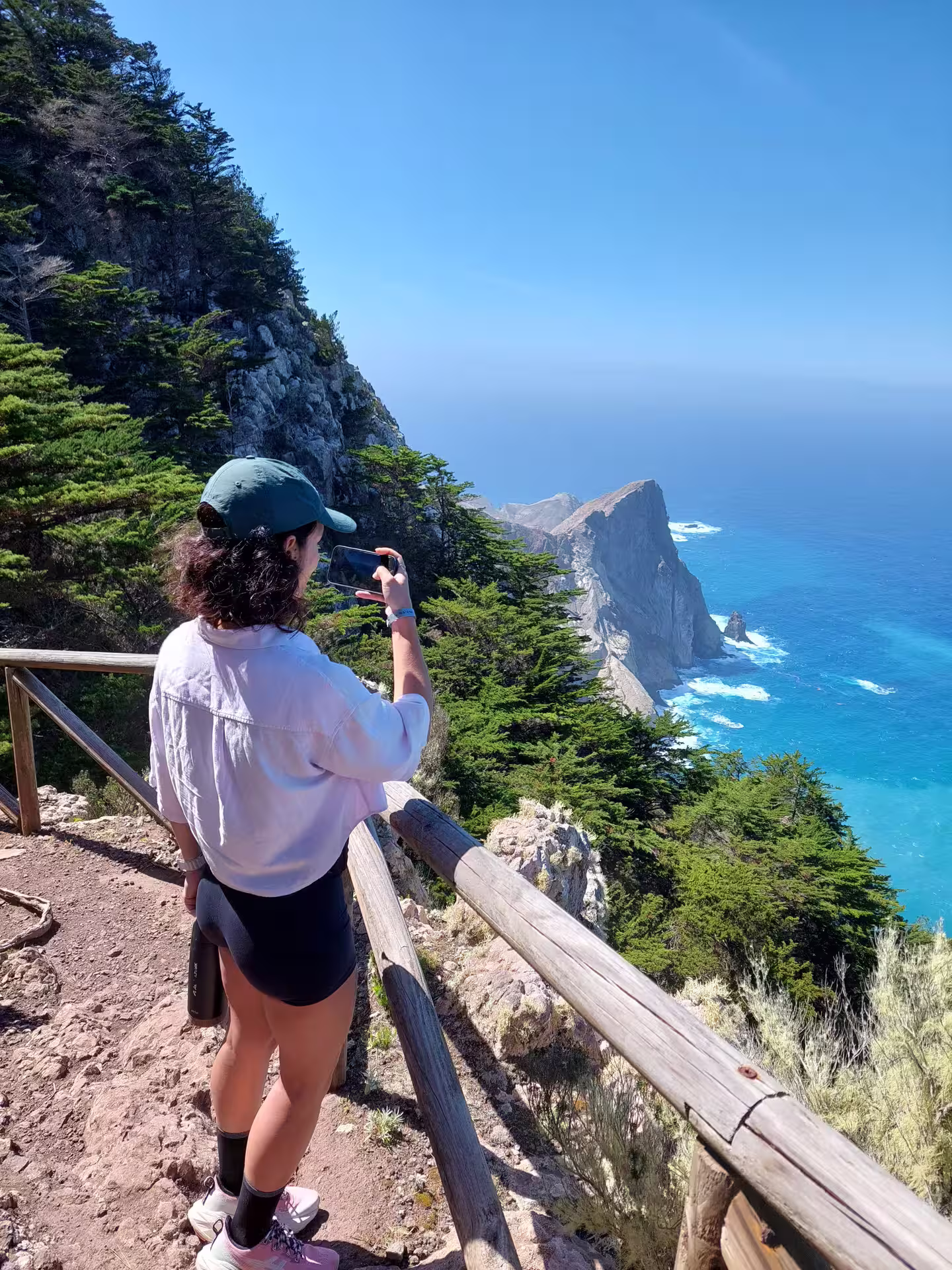 A hiker enjoys a stunning coastal view from a cliffside trail, capturing the essence of a tailored hiking adventure.