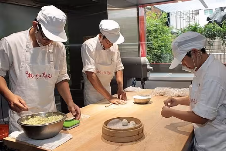Chefs expertly crafting xiaolongbao dumplings at Taipei Hungzhou Xiaolongbao, showcasing authentic culinary skills.
