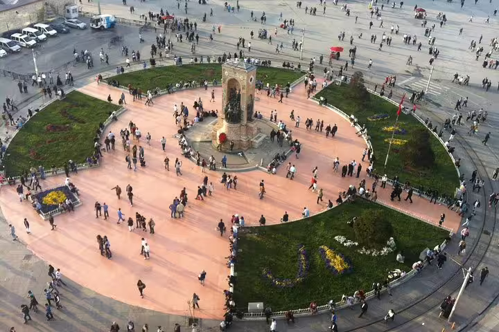 Aerial view of Taksim Square, Istanbul, bustling with people around the Republic Monument, showcasing vibrant city life.