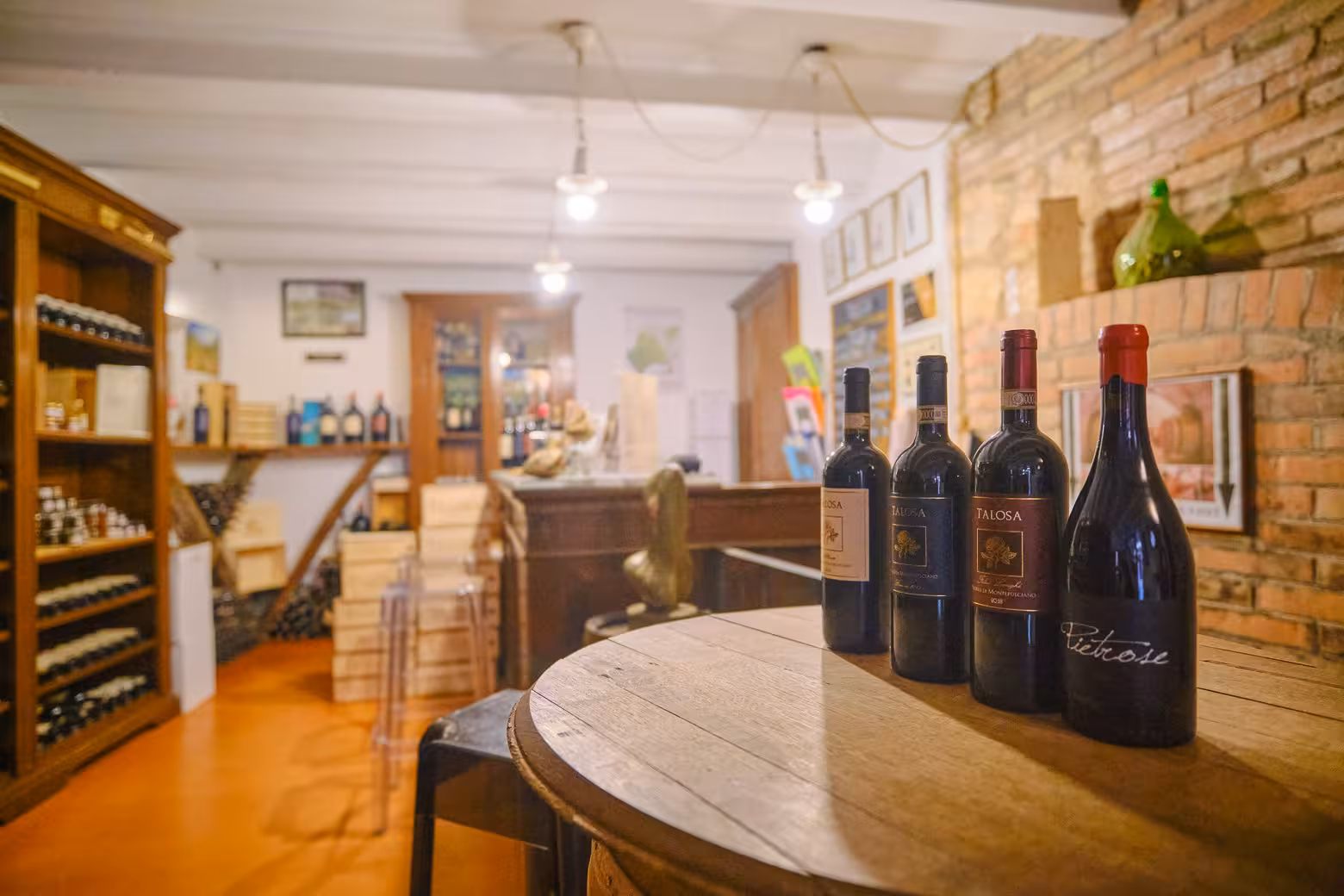 Close-up of premium Talosa wine bottles on a wooden barrel inside a cozy Montepulciano wine shop during a private tour.