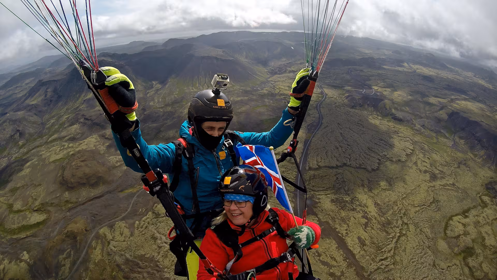 Red paraglider soaring above Blue Mountains rugged lava fields and valley, scenic tandem paragliding tour view