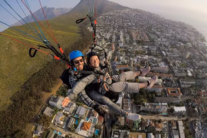 Soar above the scenic landscape of Cape Town with tandem paragliding, witnessing the vibrant city and lush mountains below.