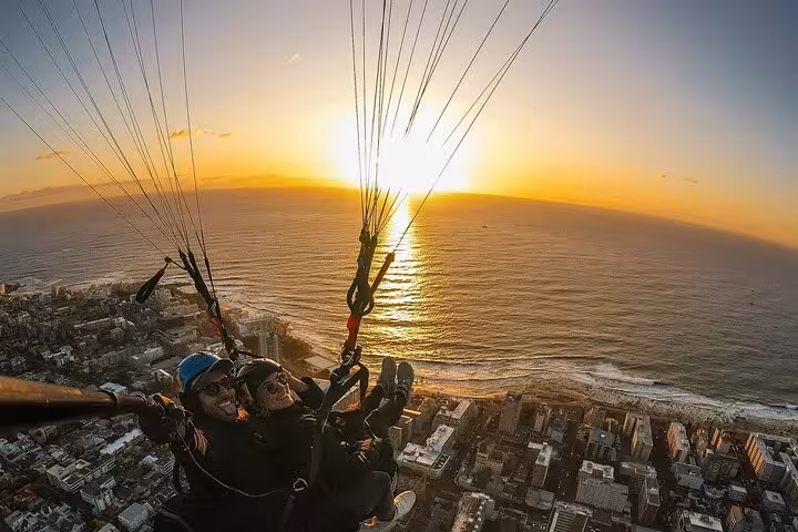 Experience breathtaking tandem paragliding over Cape Town at sunset, capturing the stunning ocean and cityscape views.