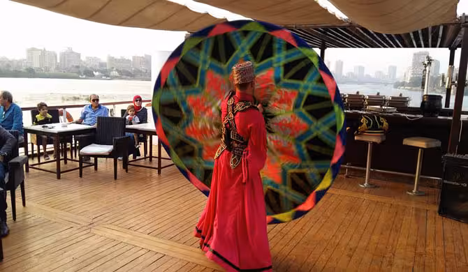 Tanoura dancer performing on Cairo Nile dinner cruise deck, live entertainment with skyline views and private transfer