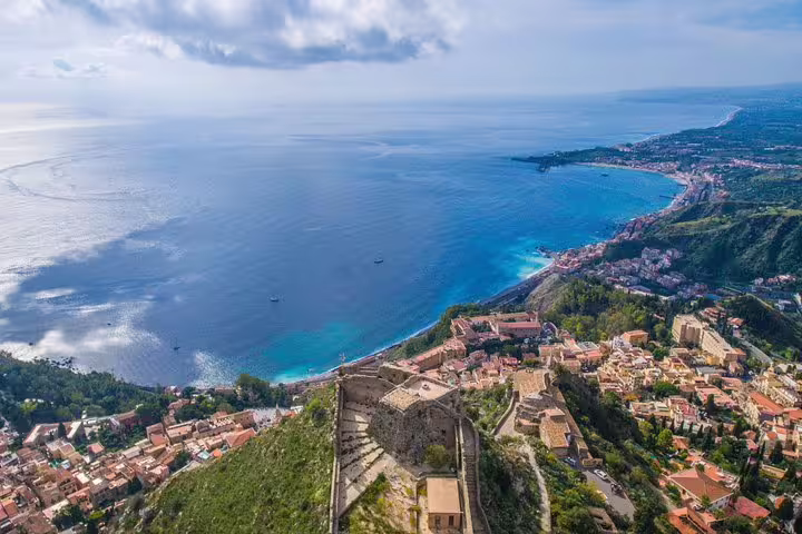 Panoramic aerial view of Taormina coastline and ancient hilltop ruins on a private Etna and Taormina tour from Cefalù