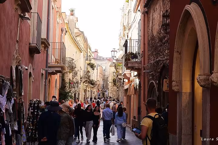 Bustling street in Taormina, Sicily, lined with vibrant shops and historic architecture, ideal for Etna and Taormina tour.