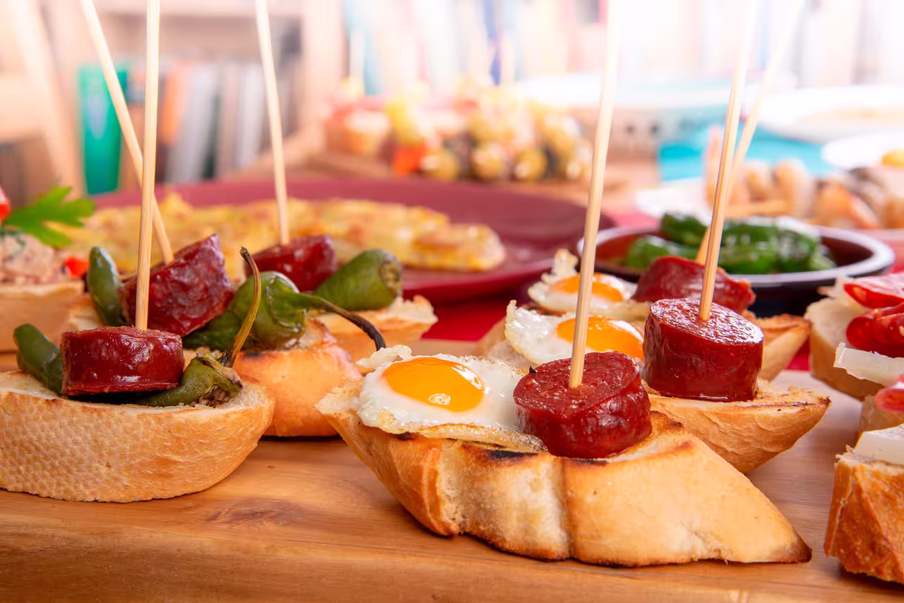 Delicious tapas with chorizo, fried eggs, and peppers on crusty bread, perfect for an authentic Spanish culinary experience.