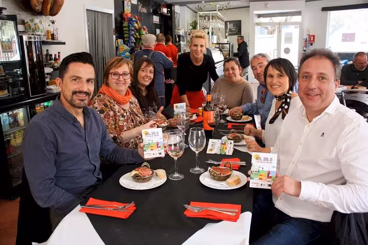 Group enjoying a tapas tasting experience with drinks at a cozy restaurant in Santiago Old Town, featuring diverse tapas plates.