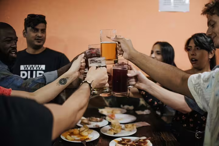 Group enjoying drinks and diverse tapas in a lively Madrid setting, perfect for a cultural and culinary tour experience.