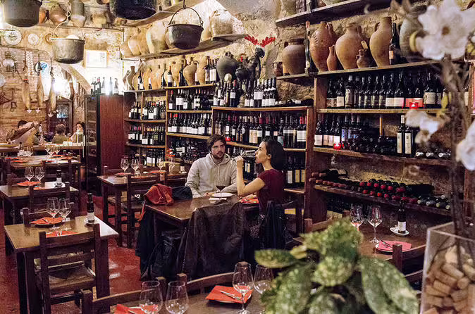 Cozy wine bar setting with rustic decor, featuring a couple enjoying tapas and wine surrounded by shelves of bottles.