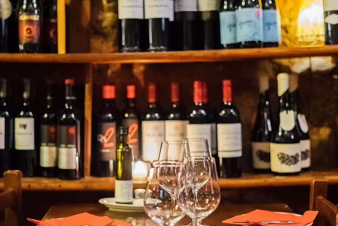 Intimate wine tasting setup with glasses and bottles on a wooden table, ideal for a tapas and wine experience.