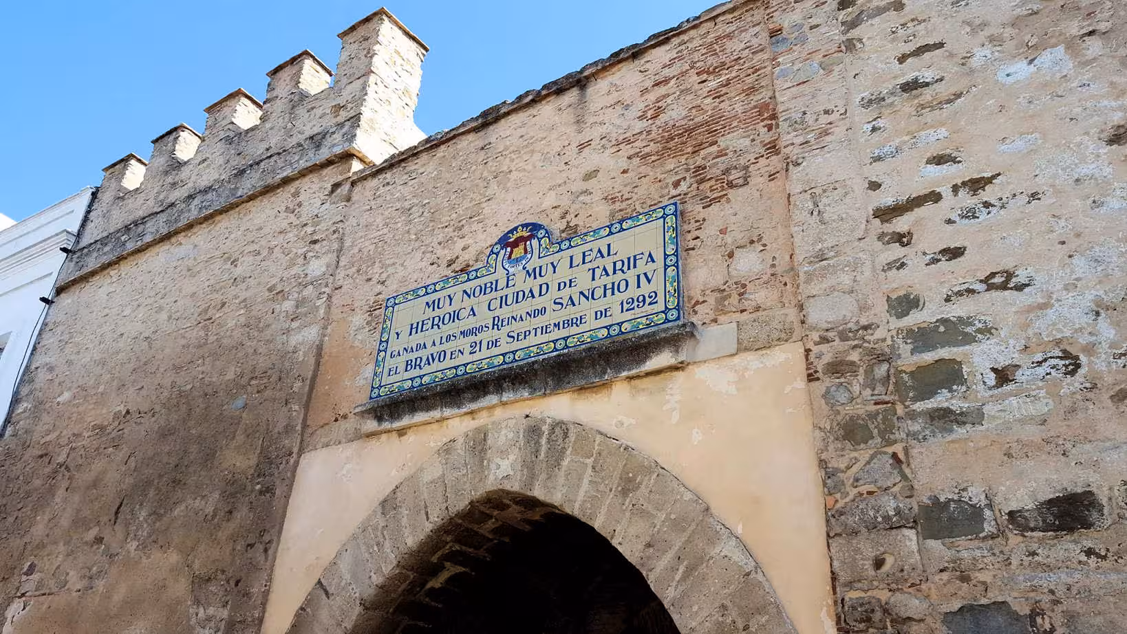 Historic archway and sign in Tarifa, showcasing the city's rich cultural heritage and architecture.
