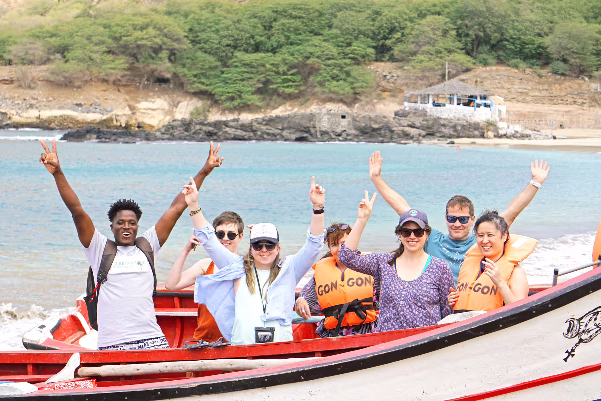 Excited tourists in life vests on a boat at Tarrafal Beach, enjoying a scenic tour with lush landscapes.