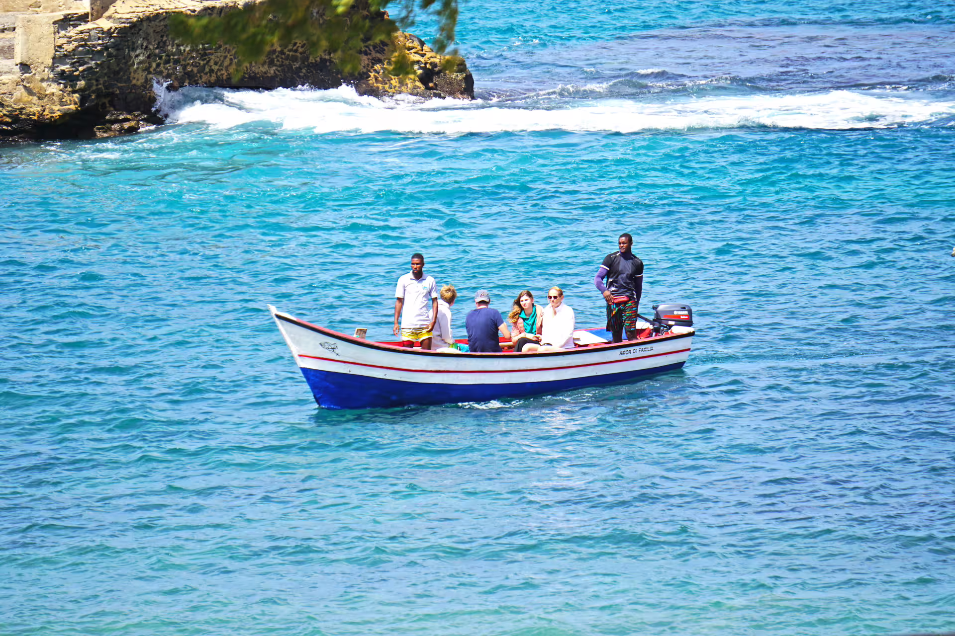 Tourists on a small boat cruising the clear turquoise waters near Tarrafal Beach, Cape Verde.
