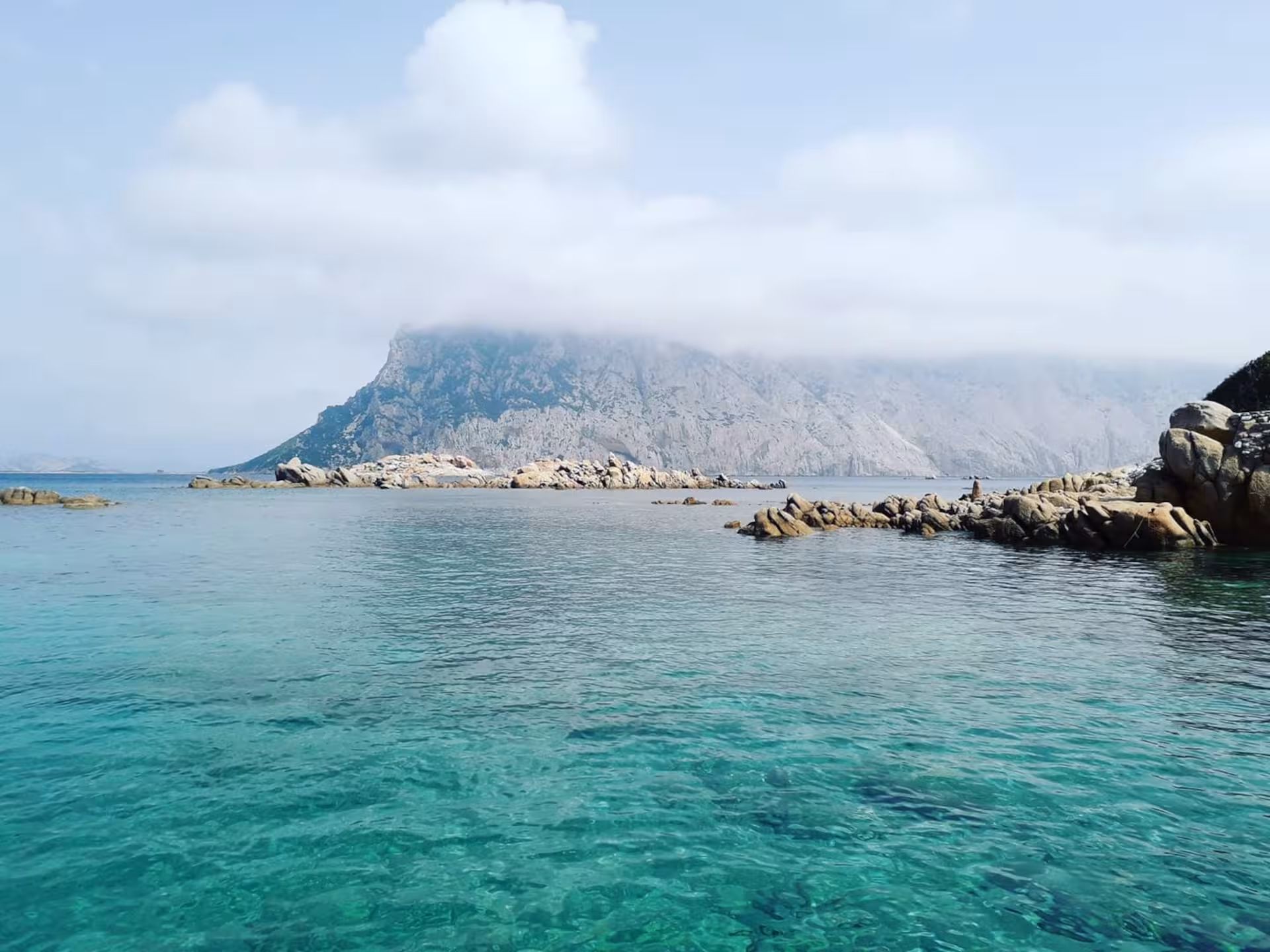 Scenic view of Tavolara Island's rocky coastline with turquoise waters on a boat tour from Porto San Paolo.