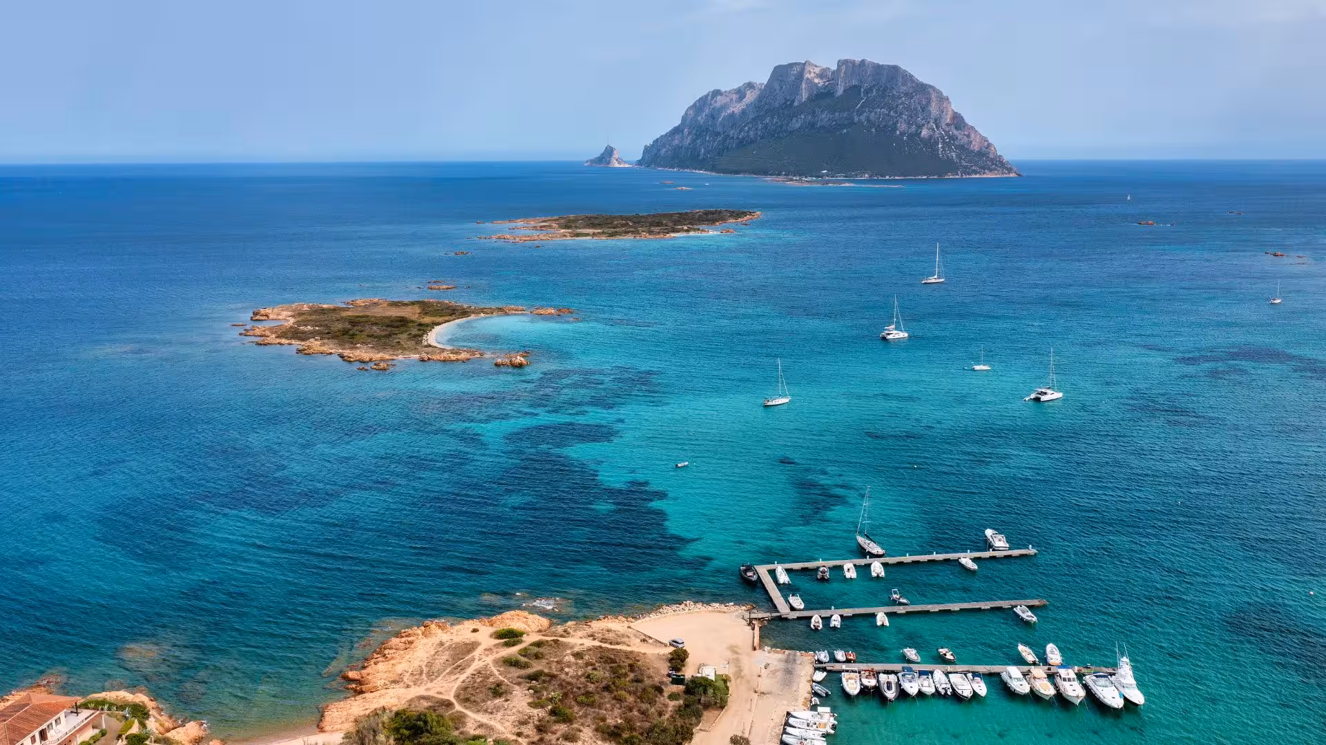 Aerial view of Tavolara Island with turquoise waters and yachts, ideal for a private dinghy tour from Porto Rotondo.