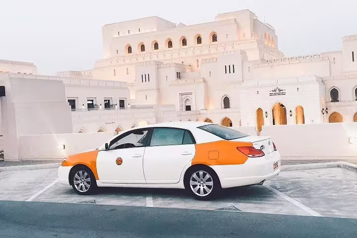 Taxi parked in front of the Royal Opera House Muscat, showcasing Oman's blend of modern and traditional architecture.