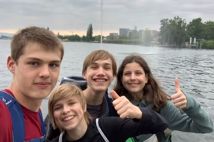 Teens smiling by Lake Zug waterfront with fountain, on a Zug scavenger hunt and sights self-guided tour