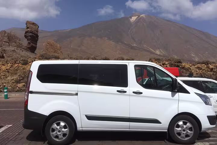 Tour van parked at Teide National Park with majestic volcanic mountains in the background.