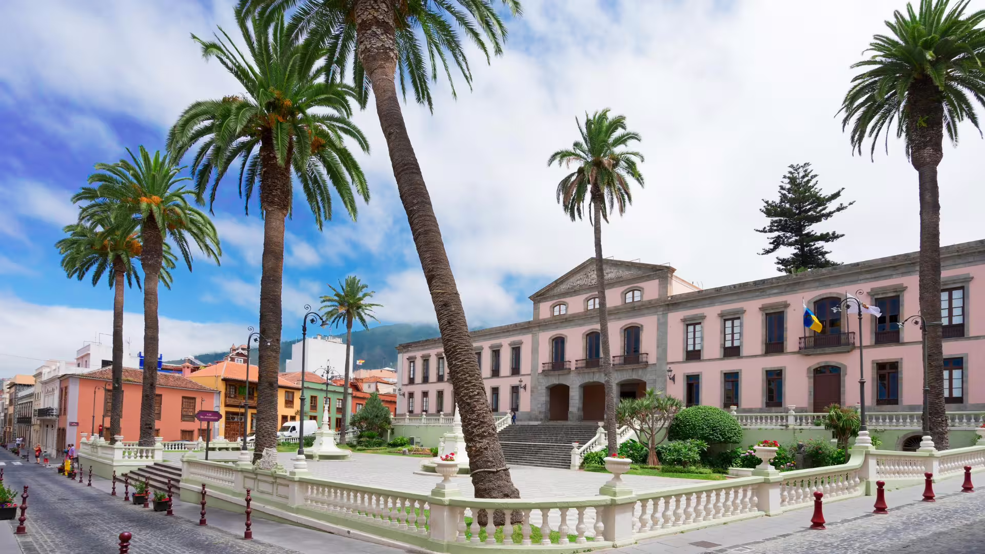 Charming town square with elegant palm trees and historic architecture under a vibrant blue sky.