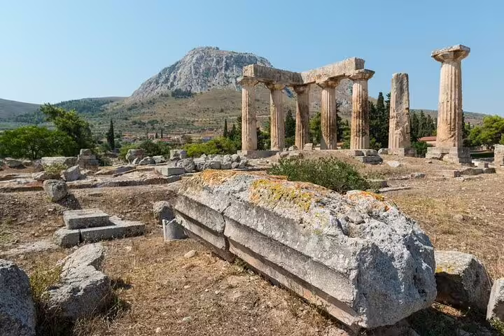 Temple of Apollo at Ancient Corinth with mountain backdrop, must-see stop on a 2-day Peloponnese tour