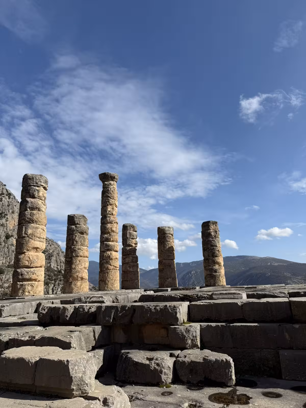 Ancient stone columns of the Temple of Apollo in Delphi with mountain views on a private day trip from Athens