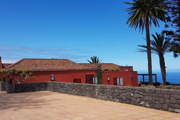 Experience the serene beauty of a traditional red villa with ocean views on the Tenerife Enogastronomic Tour.