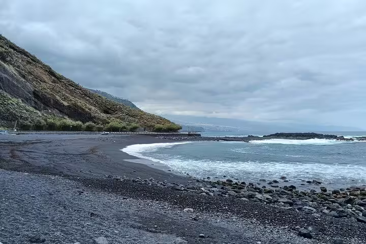 Black sand beach with rocky shoreline and ocean waves on Tenerife's north coast.