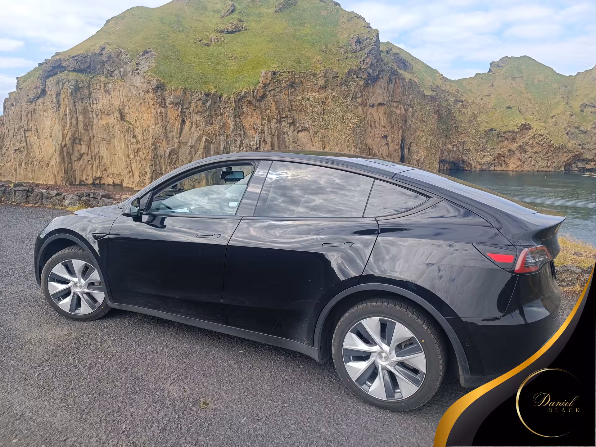 Black Tesla private airport transfer from KEF to Reykjavík, scenic coastal cliffs in Iceland backdrop