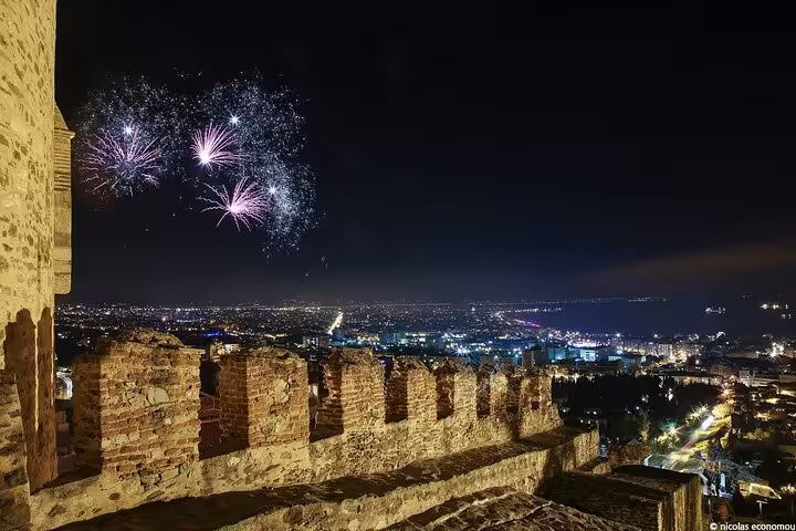 Vibrant fireworks illuminate the night sky over Thessaloniki, viewed from ancient city walls during a private custom tour.