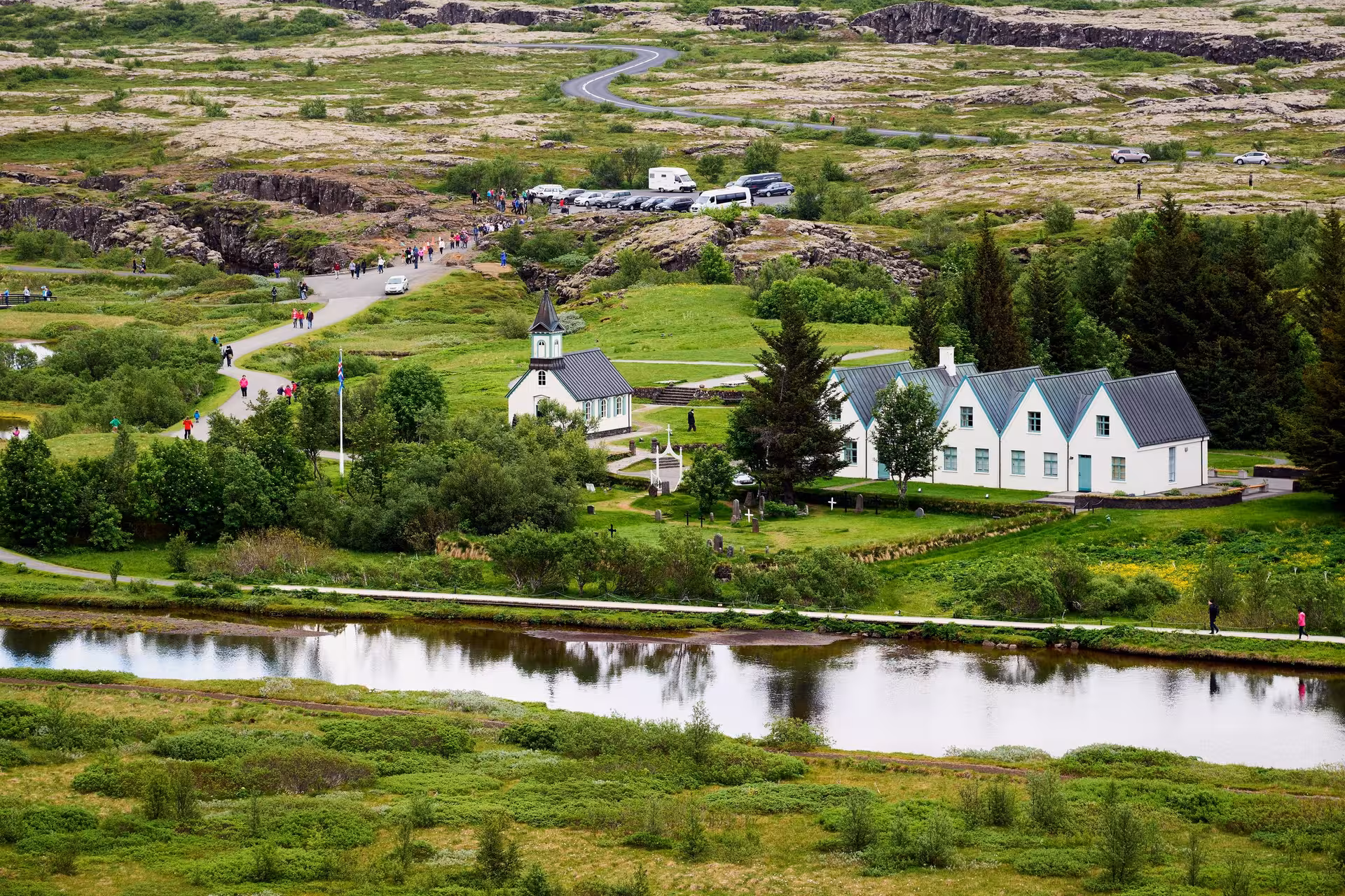 Scenic view of Thingvellir National Park featuring lush greenery, a church, and Icelandic landscape.