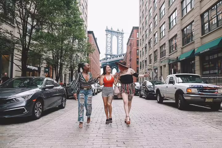 Three friends walking in Dumbo, Brooklyn with the Manhattan Bridge backdrop during a personal travel photo tour in NYC.