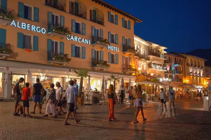 Evening stroll by illuminated Albergo Carcani hotel, capturing vibrant nightlife in Ticino's charming streets.