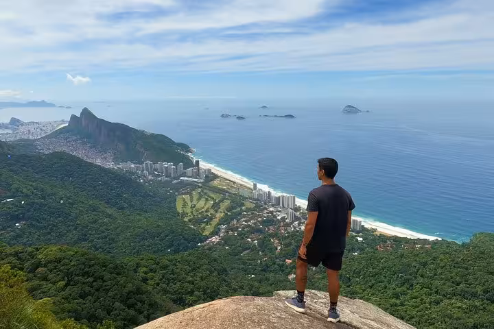Traveler enjoys panoramic ocean and forest views from a high vantage point in Tijuca Forest, Rio de Janeiro.