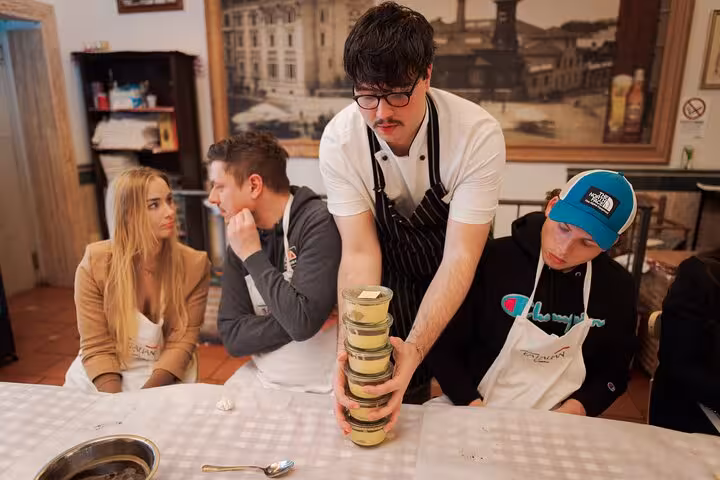 Instructor presenting tiramisu during a cooking class in Rome's Piazza Navona, surrounded by attentive participants.