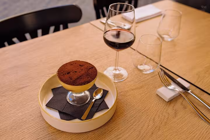 Elegant tiramisu and red wine on a wooden table set for a cooking class in Rome's Piazza Navona.
