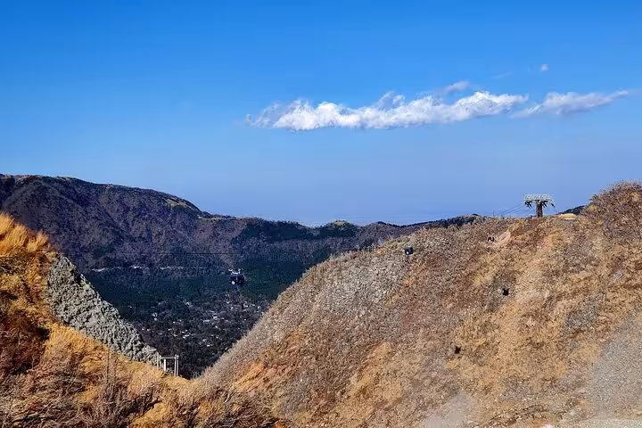 Panoramic view of cable cars over Owakudani valley, showcasing the dramatic terrain on a Hakone private tour.
