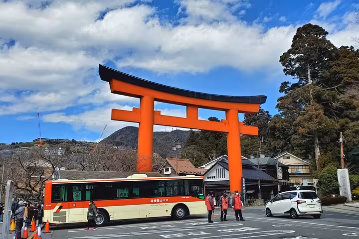 Vibrant red torii gate in Hakone with tourists and a bus, showcasing cultural stops on the Tokyo to Hakone private tour.