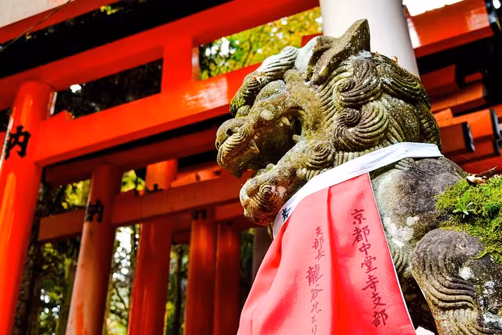 Close-up of a guardian lion statue with a red bib at a Shinto shrine, featured on the Tokyo to Kamakura tour.