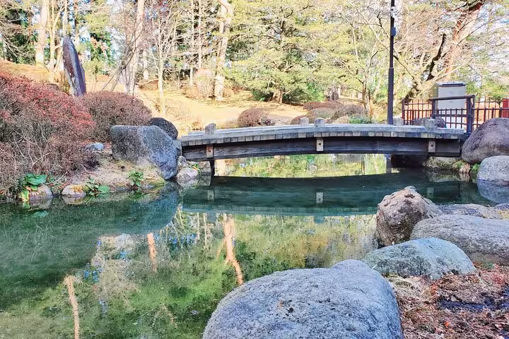 Discover a tranquil garden pond with a rustic wooden bridge in Nikko, featured on the Tokyo to Nikko tour.