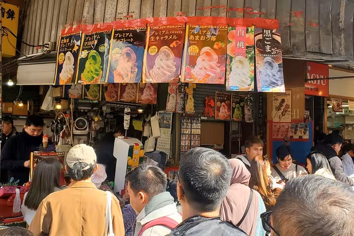 Tourists lining up for colorful ice cream treats at a vibrant stall in Tokyo's Tsukiji Outer Market.