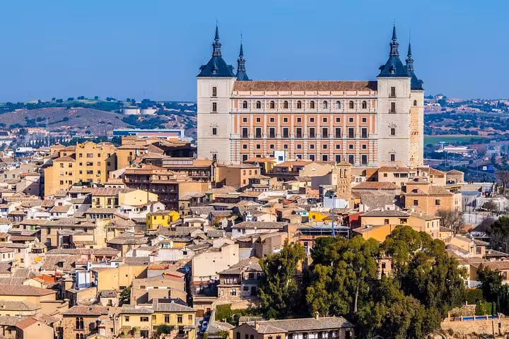 Panoramic view of Toledo's historic skyline with the majestic Alcázar dominating the cityscape under a clear blue sky.