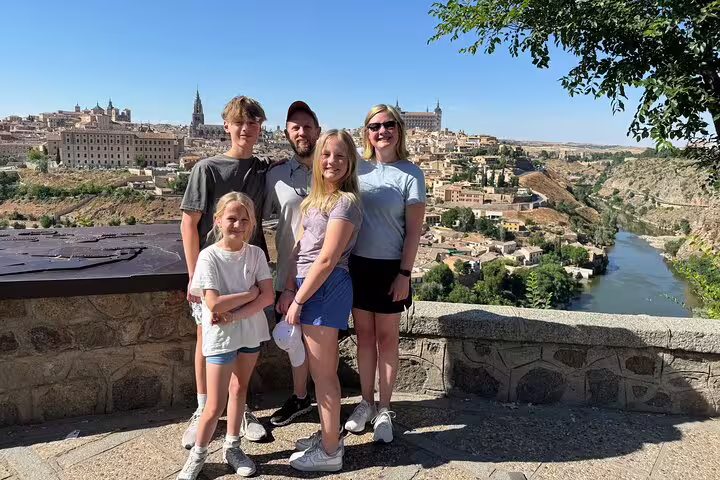 Family posing with scenic backdrop of Toledo’s historic architecture and river, showcasing cultural charm of the city.