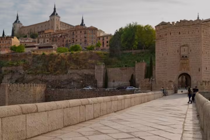 Toledo half-day private minivan tour view from Puente de Alcántara to the historic city walls and Alcázar